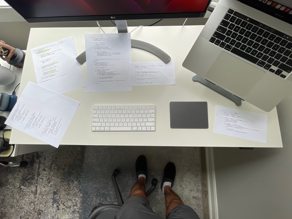 Papers containing code snippets spread on a desk.