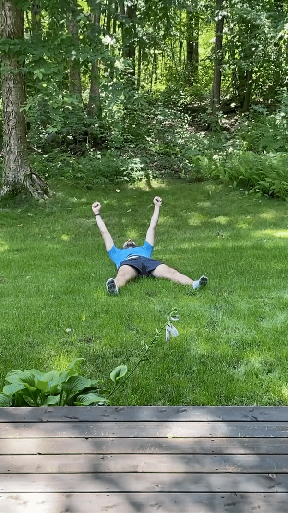 Looping gif of the author throwing his arms in the air while laying in grass.